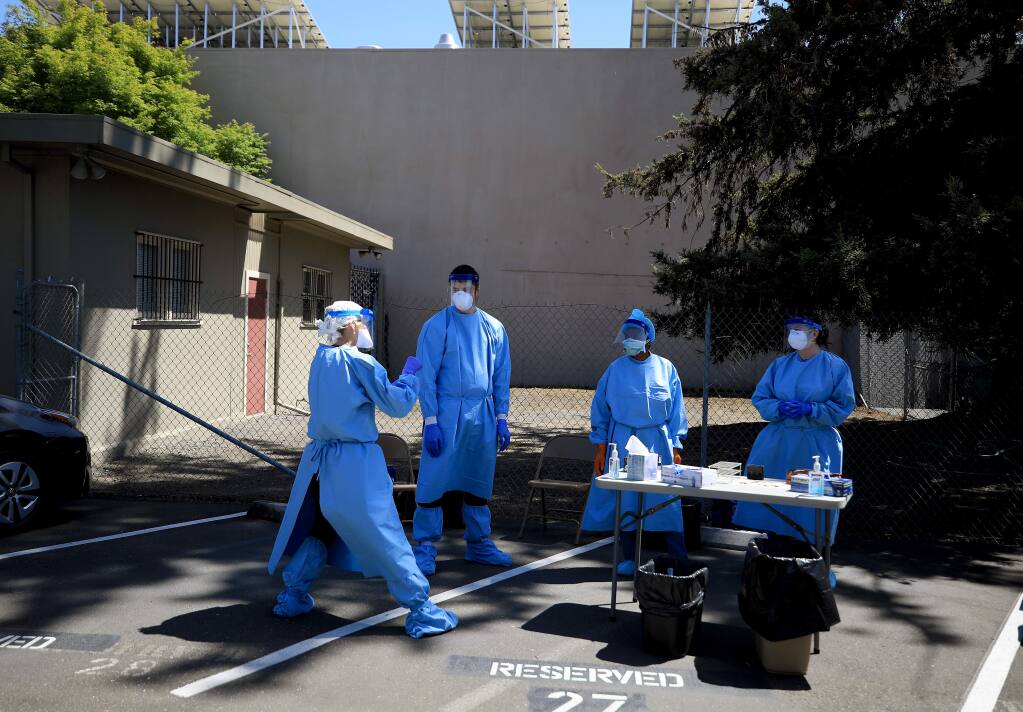 Sonoma County Public Health nurses, from left, Maggie Wideau, Jacob Soled, Sylvia Brown and Katy Jenkins take a break from the heat during a drive-up coronavirus testing and tracing clinic, April 22, 2020 in Santa Rosa. (Kent Porter / The Press Democrat) 2020